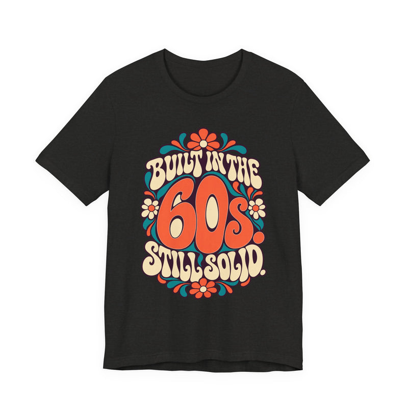 Built in the 60s. Still Solid Tee in Black Heather, front view with groovy retro lettering