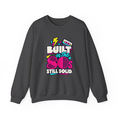 Built in the 80s. Still Solid Crewneck Sweatshirt in Dark Heather, front view with neon cassette design