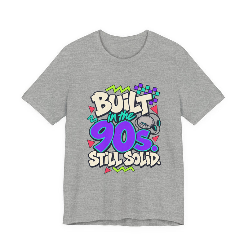 Built in the 90s. Still Solid Tee in Athletic Heather, front view with graffiti-style lettering